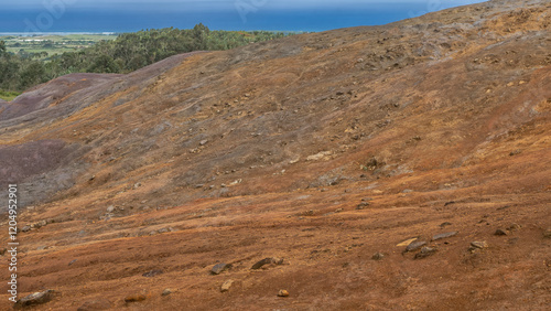 The unique 23 coloured earth of Mauritius. Colorful sand hills in the foreground, in the distance - a valley with green vegetation, a blue ocean. La Vallée Des Couleurs Nature Park  