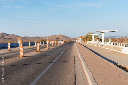 Travel on a road street freeway or highway under road construction with lane closure speed limit signs and fine warning in golden hour after sunrise or sunset