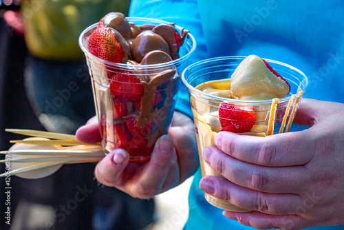 two punnets of strawberries one with caramel topping the other with chocolate bought at a fair