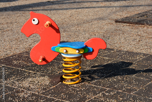 A red spring-mounted rocking horse on a children's playground