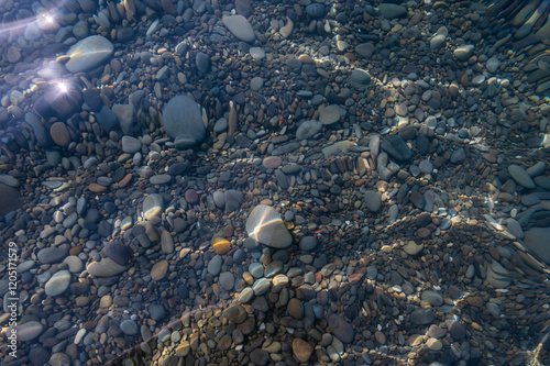 Obraz na płótnie Underwater pebble backgrounds. Colorful stones sea bottom in the sun rays. View from above through clear water. Seascape wallpaper texture. Defocus. w salonie