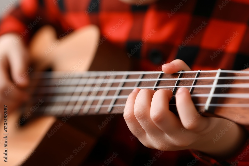 Obraz premium Child plays ukulele while wearing a red flannel shirt in a cozy indoor setting, showcasing musical talent