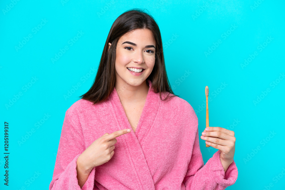 Young Brazilian woman brushing teeth isolated on blue background and pointing it Young Brazilian woman brushing teeth isolated on blue background and pointing it
