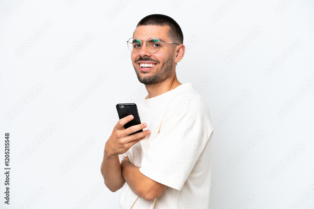 Young caucasian man isolated on white background holding a mobile phone and with arms crossed Young caucasian man isolated on white background holding a mobile phone and with arms crossed