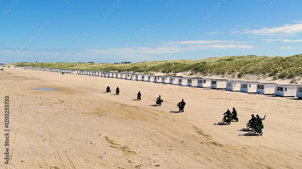 Drone follows a small group of people driving mopeds on a beach Drone follows a small group of people driving mopeds on a beach