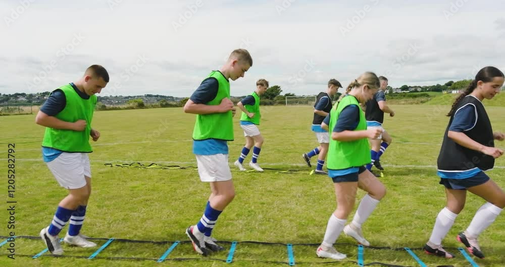 Male and female soccer players warming up and avoiding obstacles with coach on pitch Male and female soccer players warming up and avoiding obstacles with coach on pitch