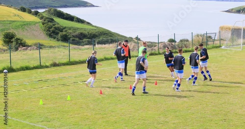 Male and female soccer players warming up and coach on pitch