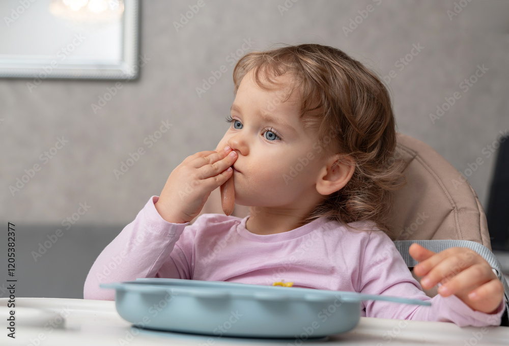 A toddler enjoying her meal with a focused expression in a cozy home setting A toddler enjoying her meal with a focused expression in a cozy home setting