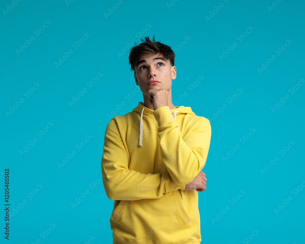 portrait of pensive casual man holding chin and looking up