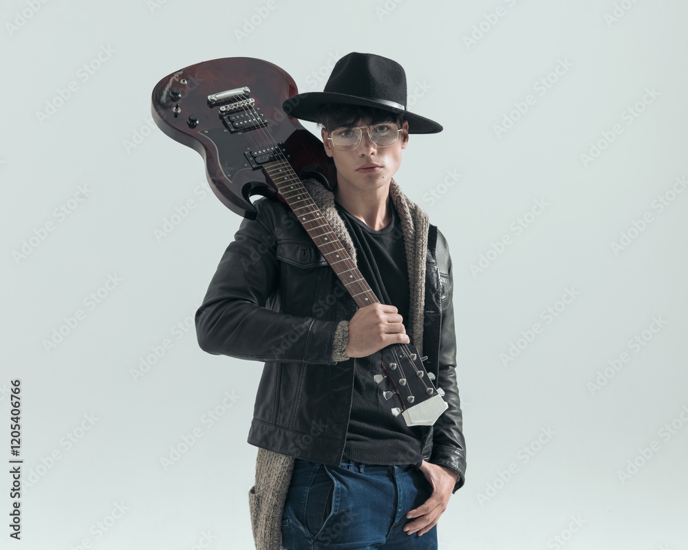 young fashion man with hat and glasses holding guitar on his shoulder young fashion man with hat and glasses holding guitar on his shoulder