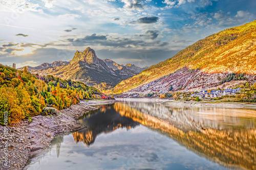 A stunning view of Panticosa village, the striking Pico de Argualas peak, and the tranquil Búbal Lake, showcasing the vibrant autumn hues of the Pyrenees, Spain. photo