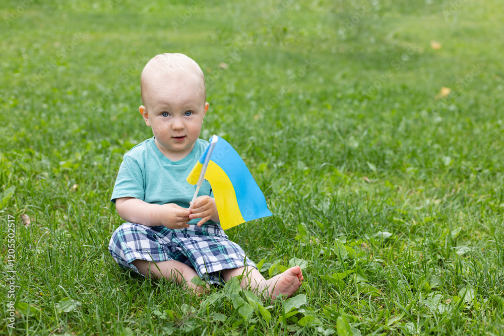 Little boy with Ukrainian flag sitting on the green grass. Little boy with Ukrainian flag sitting on the green grass.
