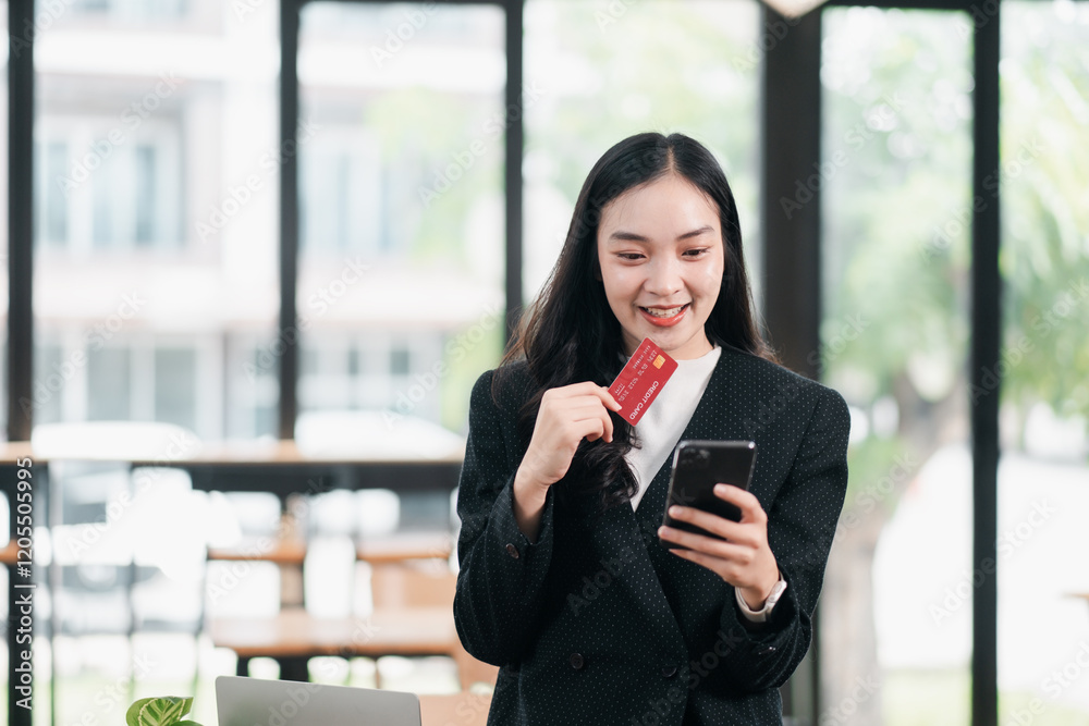 Smiling businesswoman using a smartphone and credit card for online shopping in a bright, modern office setting. Smiling businesswoman using a smartphone and credit card for online shopping in a bright, modern office setting.
