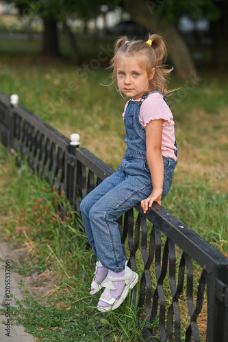 A little girl is sitting on a fence.