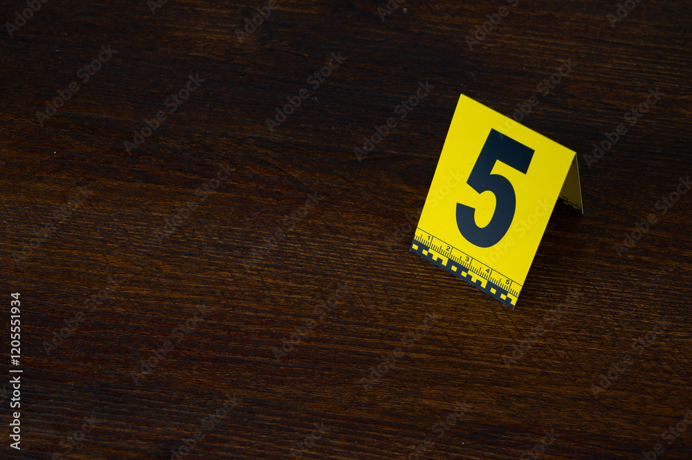 Yellow crime scene evidence marker number 5 on the floor in the room