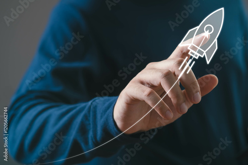 Innovative startup concept with hand drawing rocket launch symbolizing growth and success in business and technology sectors against blue background.
