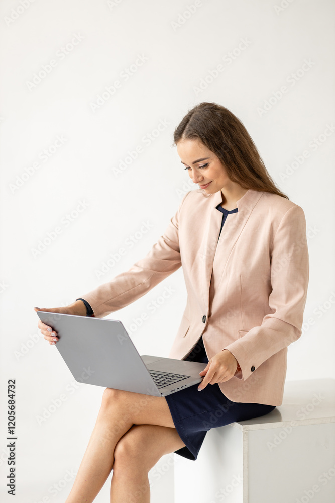 Portrait of an elegant woman in business clothes with a laptop in her hands sitting on an isolated white background.Vertical shot Portrait of an elegant woman in business clothes with a laptop in her hands sitting on an isolated white background.Vertical shot
