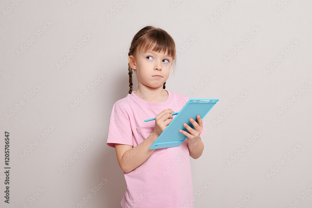 A little girl with a toy graphics tablet and a stylus A little girl with a toy graphics tablet and a stylus