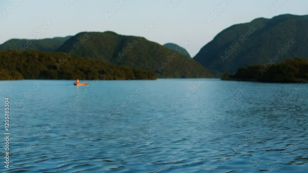 An elderly person skillfully paddles a canoe as the sun sets, casting warm light on the calm water. The peaceful surroundings create a tranquil atmosphere perfect for reflection An elderly person skillfully paddles a canoe as the sun sets, casting warm light on the calm water. The peaceful surroundings create a tranquil atmosphere perfect for reflection