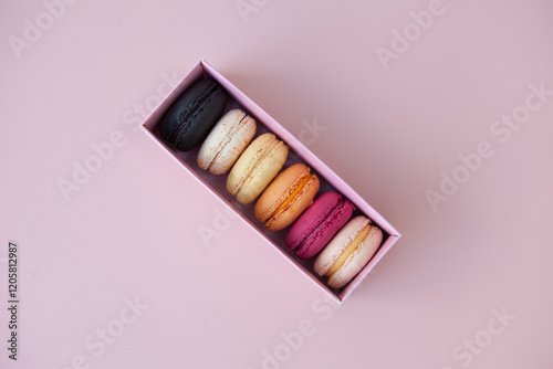 sweet meringue box. Bright food photography of macroons, various macarons, from above on a vibrant pink background with crumbs and copyspace-French macaroon