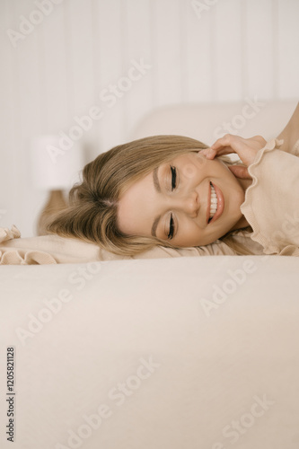 Obraz na płótnie Beautiful blonde woman posing on light bed in modern stylish beige interior w salonie