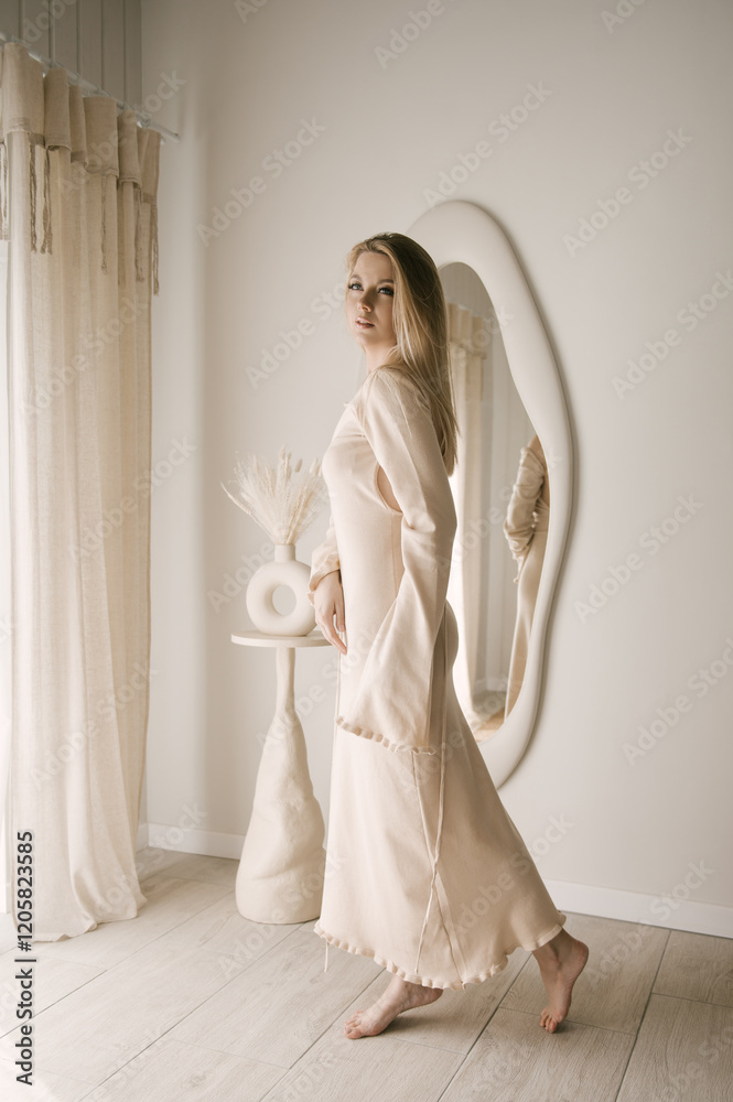 Beautiful blonde woman posing in beautiful modern stylish beige interior on photo of large mirror