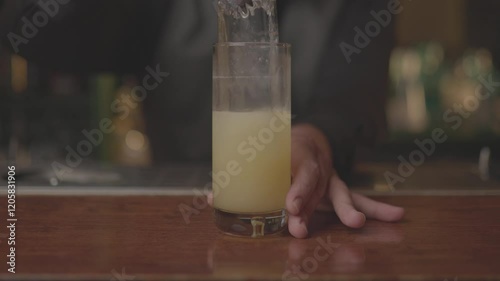 Close-up of a bartender serving a freshly made cocktail in a glass at a modern bar