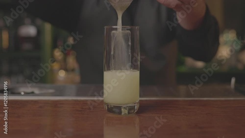 Close-up of a bartender serving a freshly made cocktail in a glass at a modern bar
