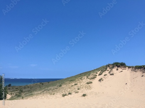 Three People Hiking on a Sand Dune Towards Lake photo