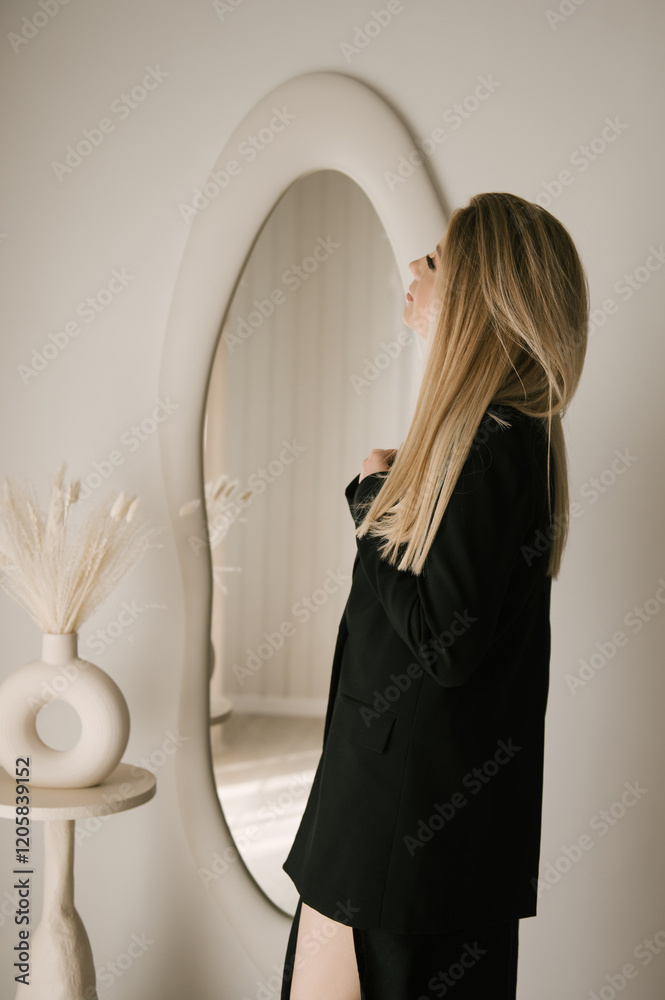 Beautiful blonde woman posing in beautiful modern stylish beige interior on photo of large mirror