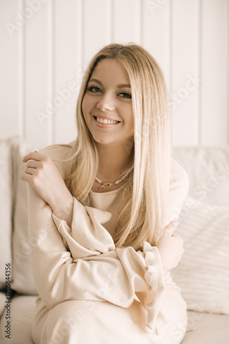 Portrait of smiling blonde woman with beautiful white smile in modern stylish beige interior