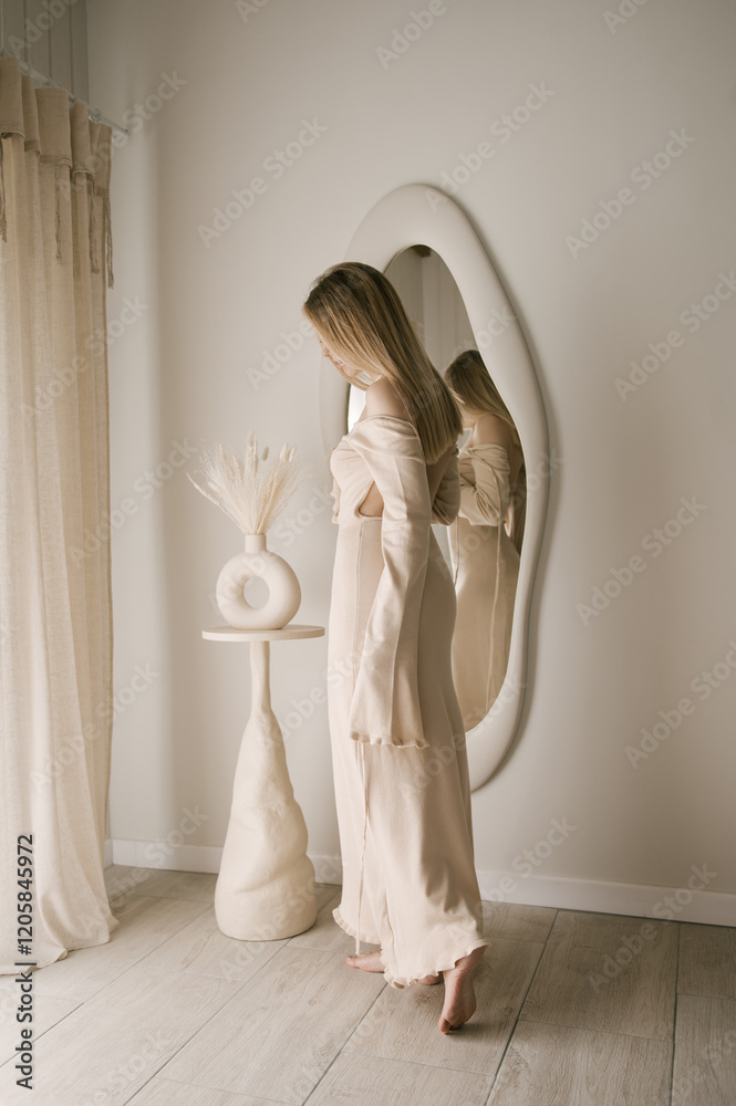Beautiful blonde woman posing in beautiful modern stylish beige interior on photo of large mirror