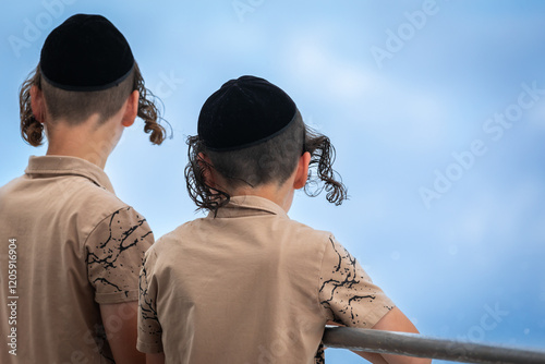 Photos Two orthodox Jewish boys, dressed identical, wearing Kippahs, Fringes flying in