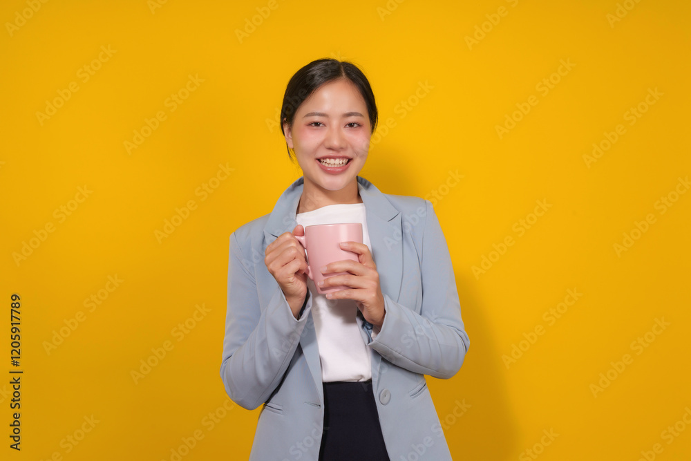 Portrait of a smiling asian businesswoman holding a pink mug on a yellow background Portrait of a smiling asian businesswoman holding a pink mug on a yellow background