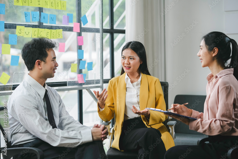 © amnaj - Business team working together on a project using sticky notes on a glass wall in a modern office
