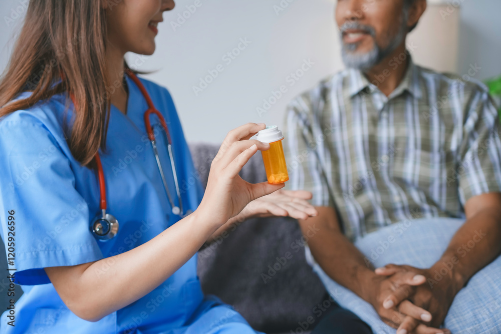 Fototapeta premium Nurse holding a pill bottle and explaining prescription to senior patient during home visit