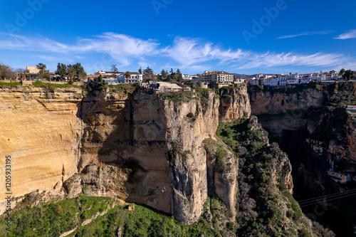 Dramatic cliff rocks and El Tajo gorge in the background supporting the village Ronda above with picturesque Andalusian scene in countryside of Spain photo