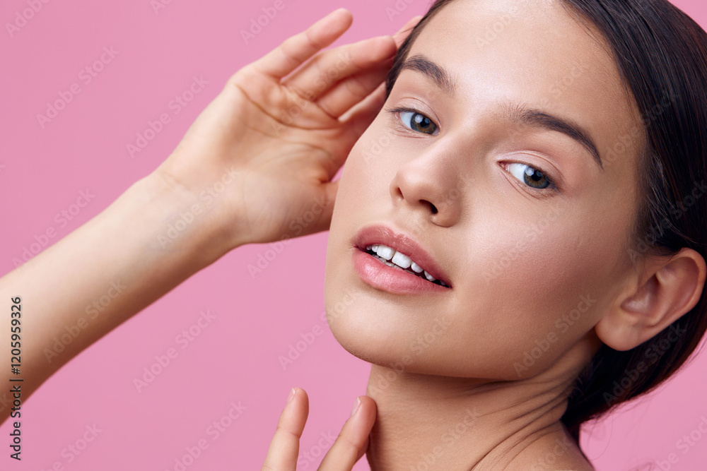 Fototapeta premium Young model with natural beauty showcasing clear skin, delicate features, and a soft expression against a pink background, representing skincare and self care
