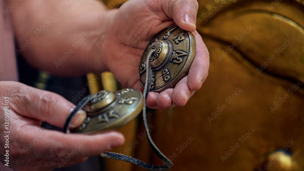 Monk holding tibetan cymbals, creating soothing sounds for meditation