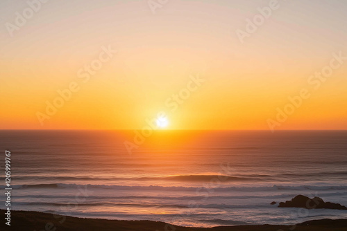 The sun is setting over the ocean, casting a warm glow on the water