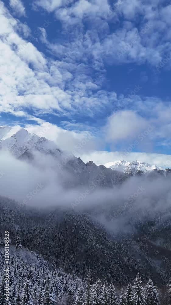 Drone Captures a Distant Mountain Peak in Winter with Sunlight, Clouds, and Fog Creating a Mystical Atmosphere Drone Captures a Distant Mountain Peak in Winter with Sunlight, Clouds, and Fog Creating a Mystical Atmosphere