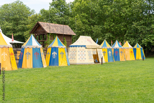 Colorful, yellow, blue medieval tents on a grassy field