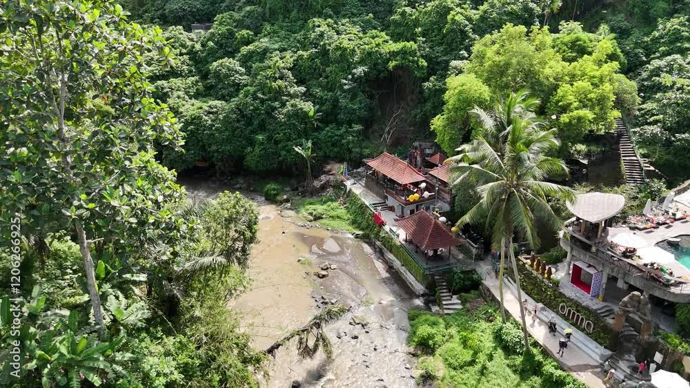 Captured by a drone, this peaceful scene features a meandering water stream, lush tropical foliage, and a sacred Hindu temple nestled in the heart of Bali’s serene landscape. Captured by a drone, this peaceful scene features a meandering water stream, lush tropical foliage, and a sacred Hindu temple nestled in the heart of Bali’s serene landscape.