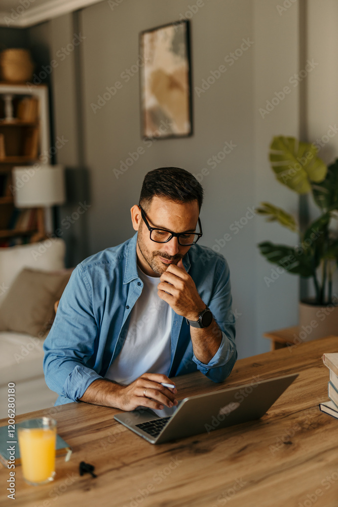Obraz premium Man seated at a table reviewing expenses while typing on his laptop