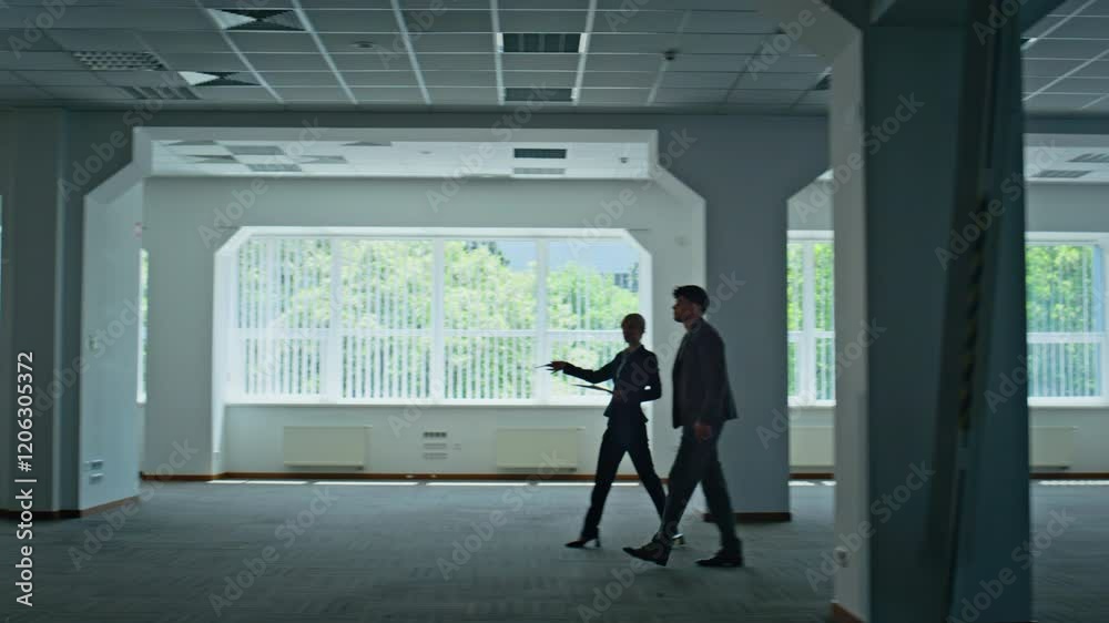 Confident couple walking office building in suits. Colleagues discussing work Confident couple walking office building in suits. Colleagues discussing work