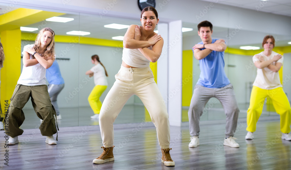 Fototapeta premium Class of young fit teenagers in casual wear dancing together during training in spacious studio