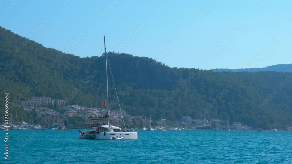 Catamaran sail by shimmering harbour. Small catamaran sailing on sea blue waves against tropical bay during summer time. Catamaran sail by shimmering harbour. Small catamaran sailing on sea blue waves against tropical bay during summer time.