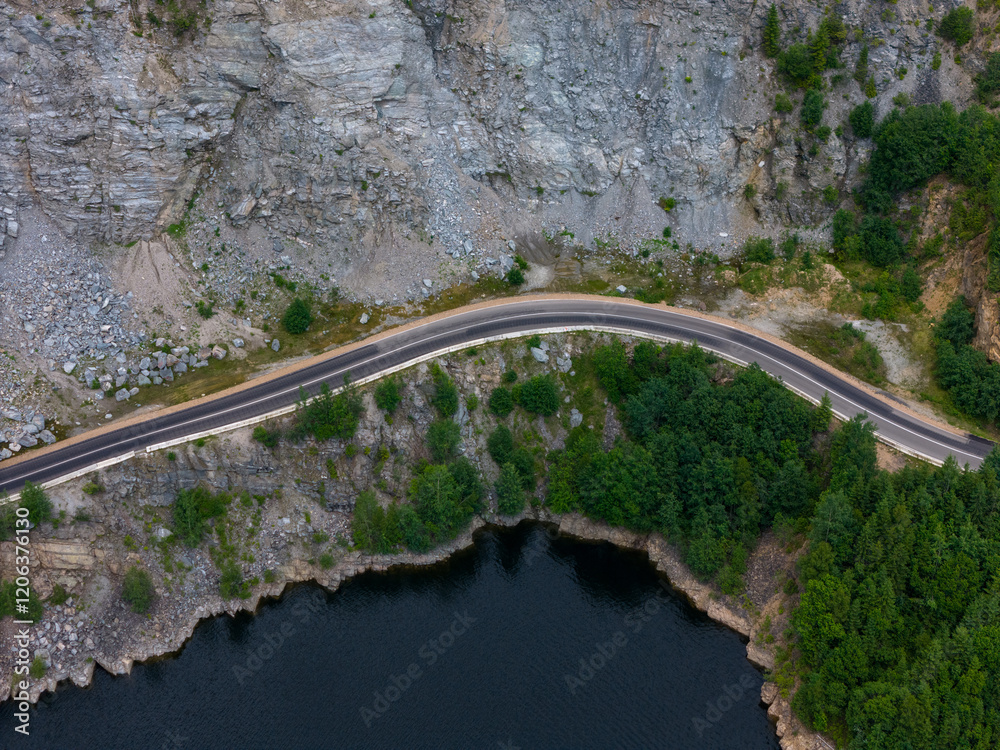 Fototapeta premium Aerial view of scenic mountain road and lake alongside