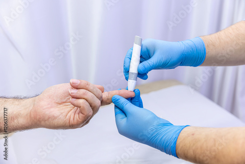 Close-up of medical worker taking patient's blood sample with finger prick kit. Medical concept. Diabetes concept. Sugar in the blood. Health concept. Glucose meter in hand.