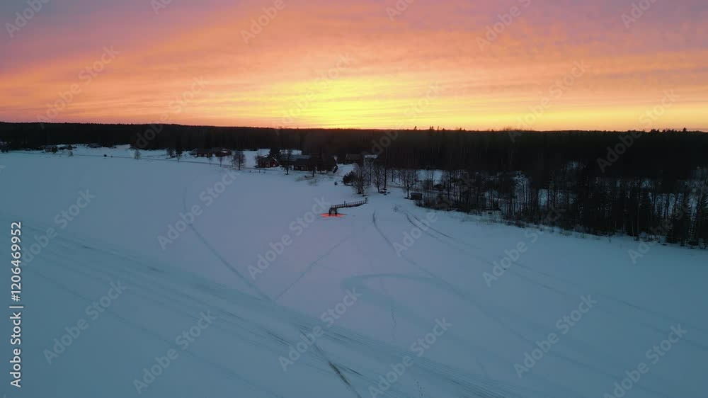 Winter ice bath and sauna location, frozen lake in Northern Finland, wide aerial view shot at sunset